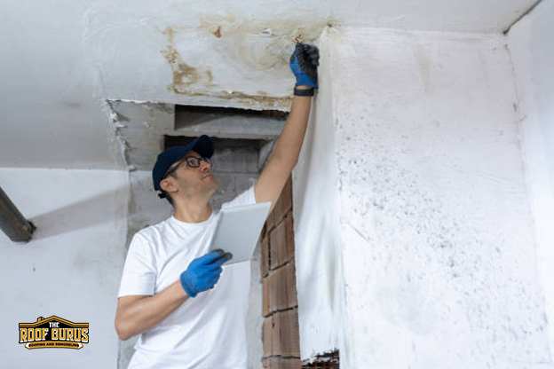 Contractor repairing interior ceiling damage from an active roof leak