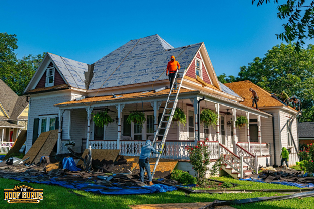 Roofers working on a roof replacement at a house